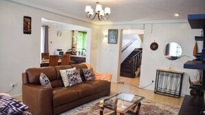 A living room with a brown leather sofa, a glass coffee table, and a patterned rug.