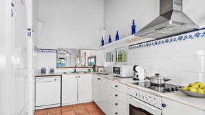 Een moderne keuken met witte kastjes, een fornuis, een magnetron en een spoelbak.