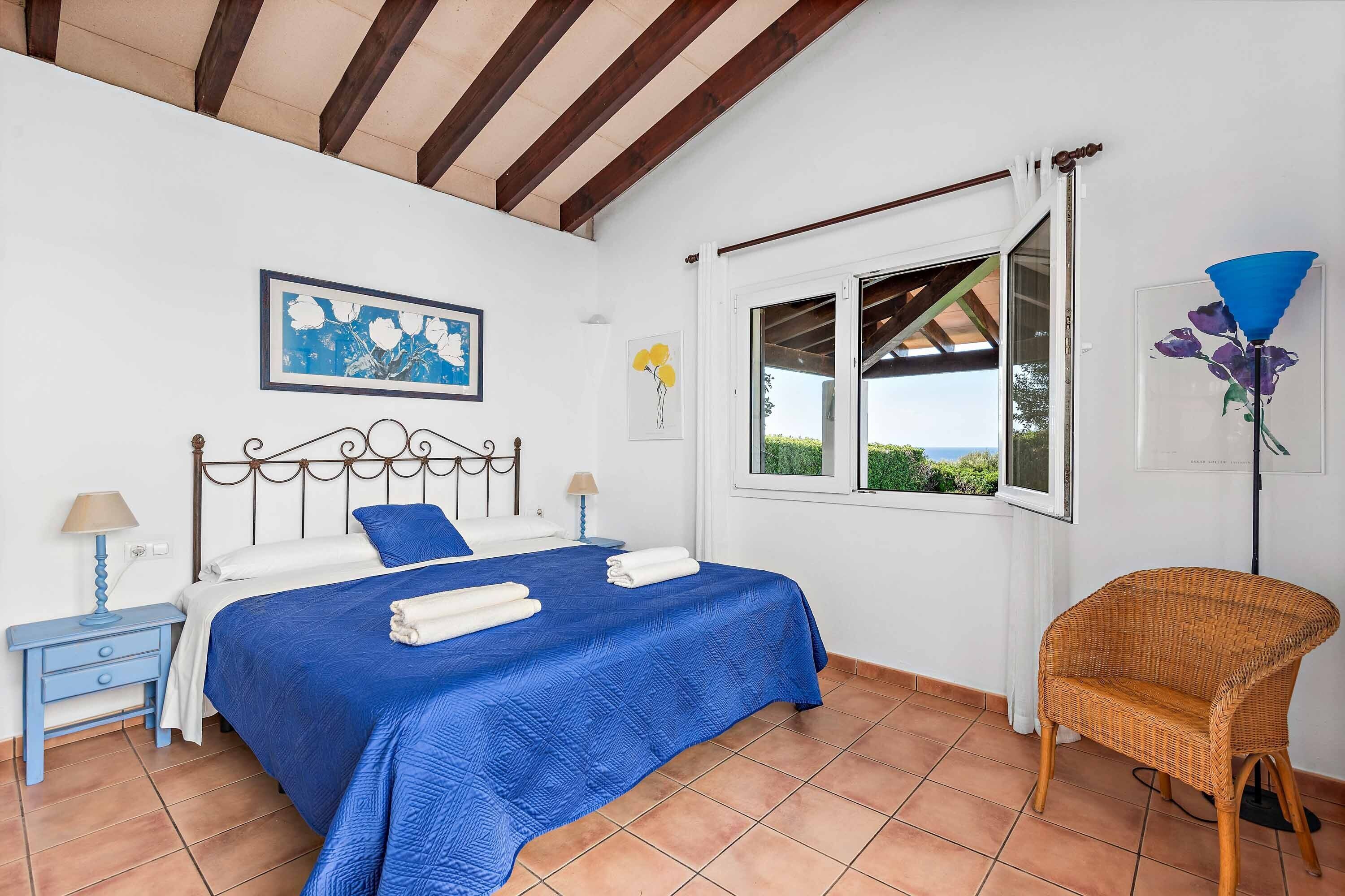 Ein Schlafzimmer mit Bett, Nachttisch, Stuhl und Fenster mit Blick.