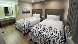 Habitación de hotel con dos camas, un baño y un espejo grande.