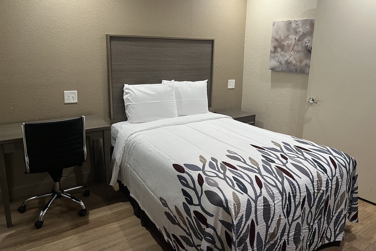 Een hotelkamer met een bed, een bureau en een stoel.