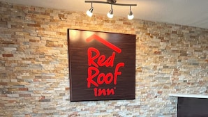 Señalización de Red Roof Inn, dos sillones de cuero, una mesita redonda y una alfombra estampada.