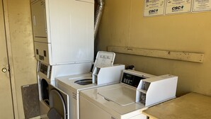 Un espace buanderie équipé d’un lave-linge et d’un sèche-linge à chargement frontal, d’un évier et d’un étendoir mural.