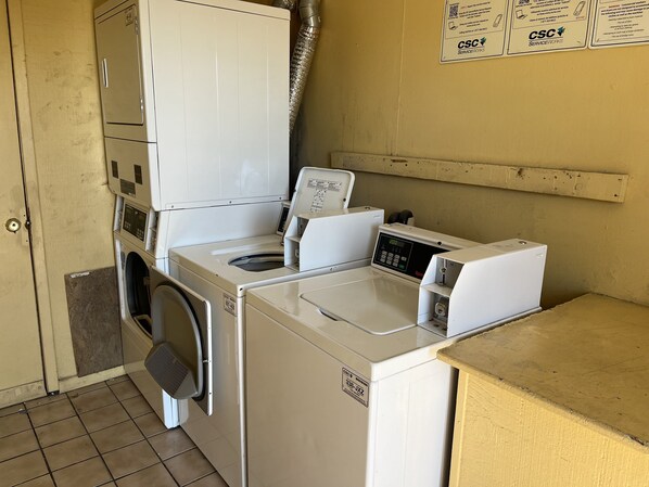 Un espace buanderie équipé d’un lave-linge et d’un sèche-linge à chargement frontal, d’un évier et d’un étendoir mural.