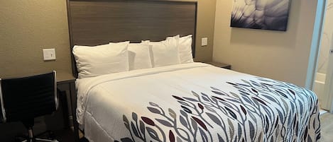 Una cama bien tendida con una colcha estampada, un cabecero de madera y un cuadro colgado en la pared.