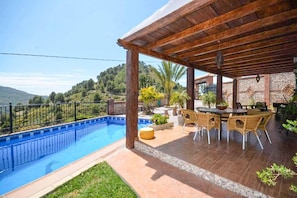 A covered outdoor area with a pool, dining table, and chairs.