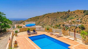 Una piscina con sillones de descanso y vistas a un paisaje montañoso.