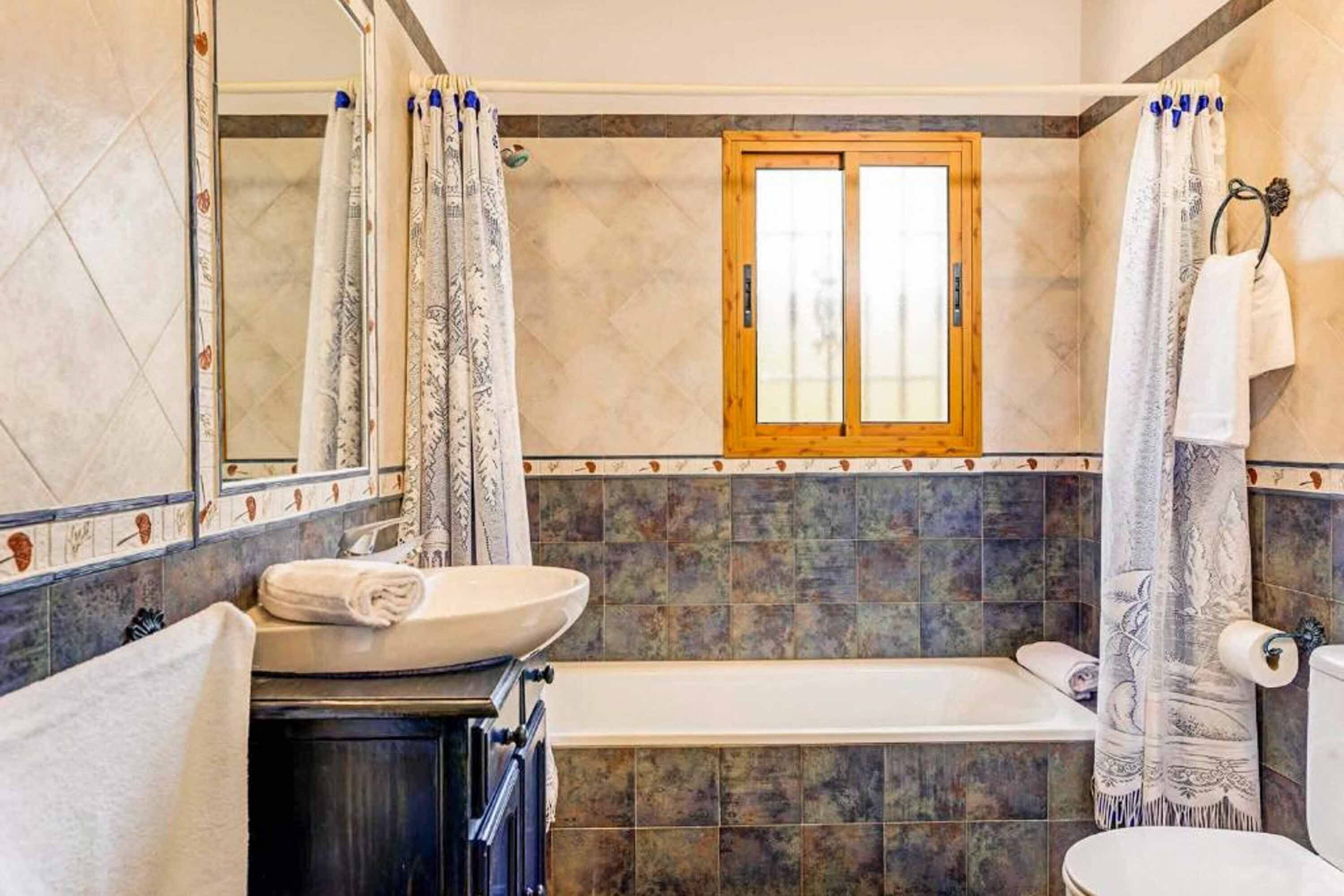 Un baño con bañera, lavamanos, inodoro y espejo.