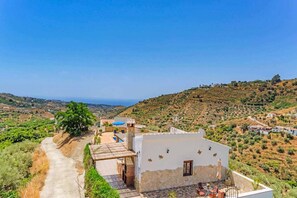 Un bâtiment blanc doté d’un patio et offrant une vue sur un paysage vallonné.