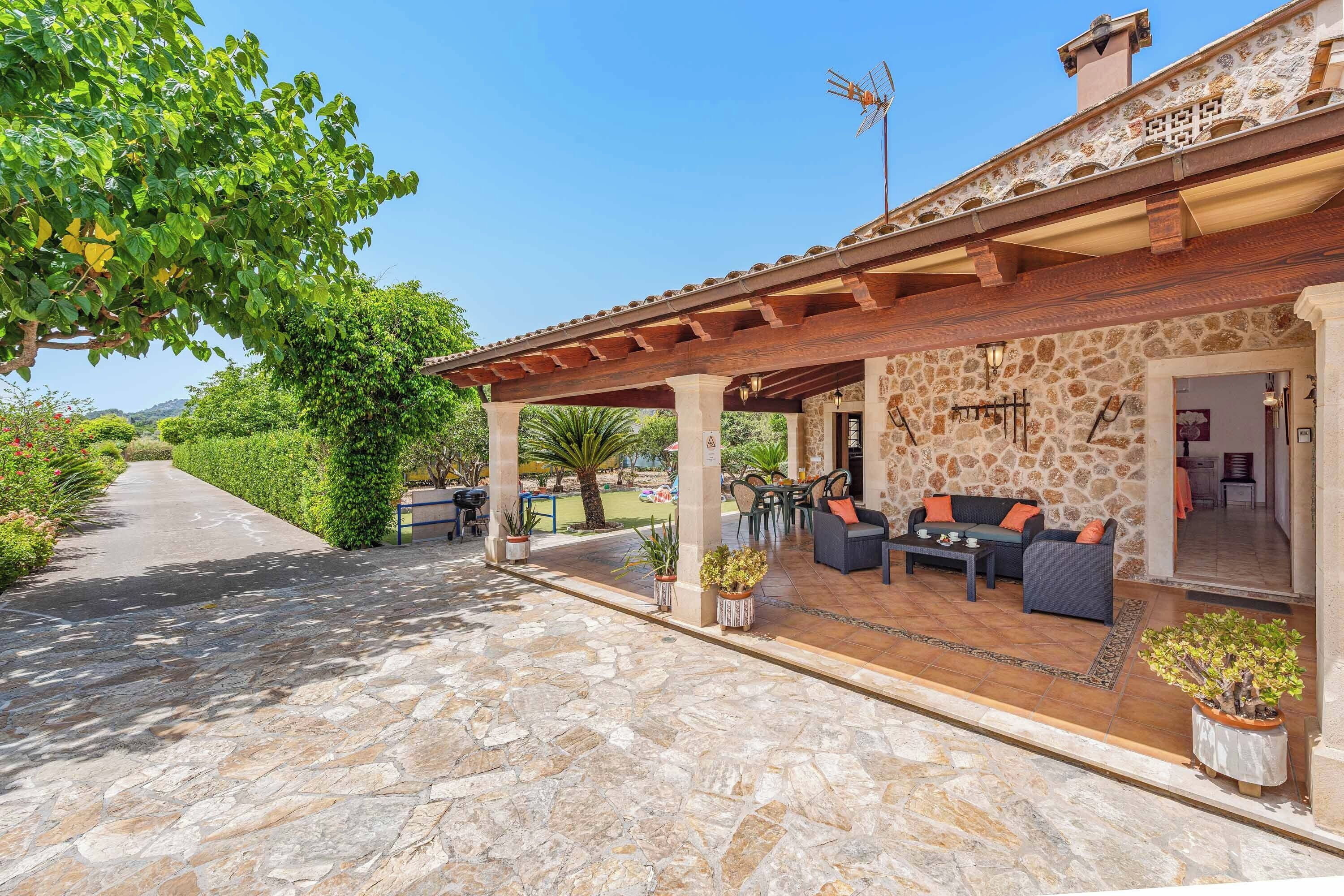 A covered outdoor seating area with stone flooring, a stone wall, and a view of a road.