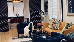 Un salon moderne comprenant un canapé, des fauteuils, une table basse et un coin repas avec un bureau et des chaises.