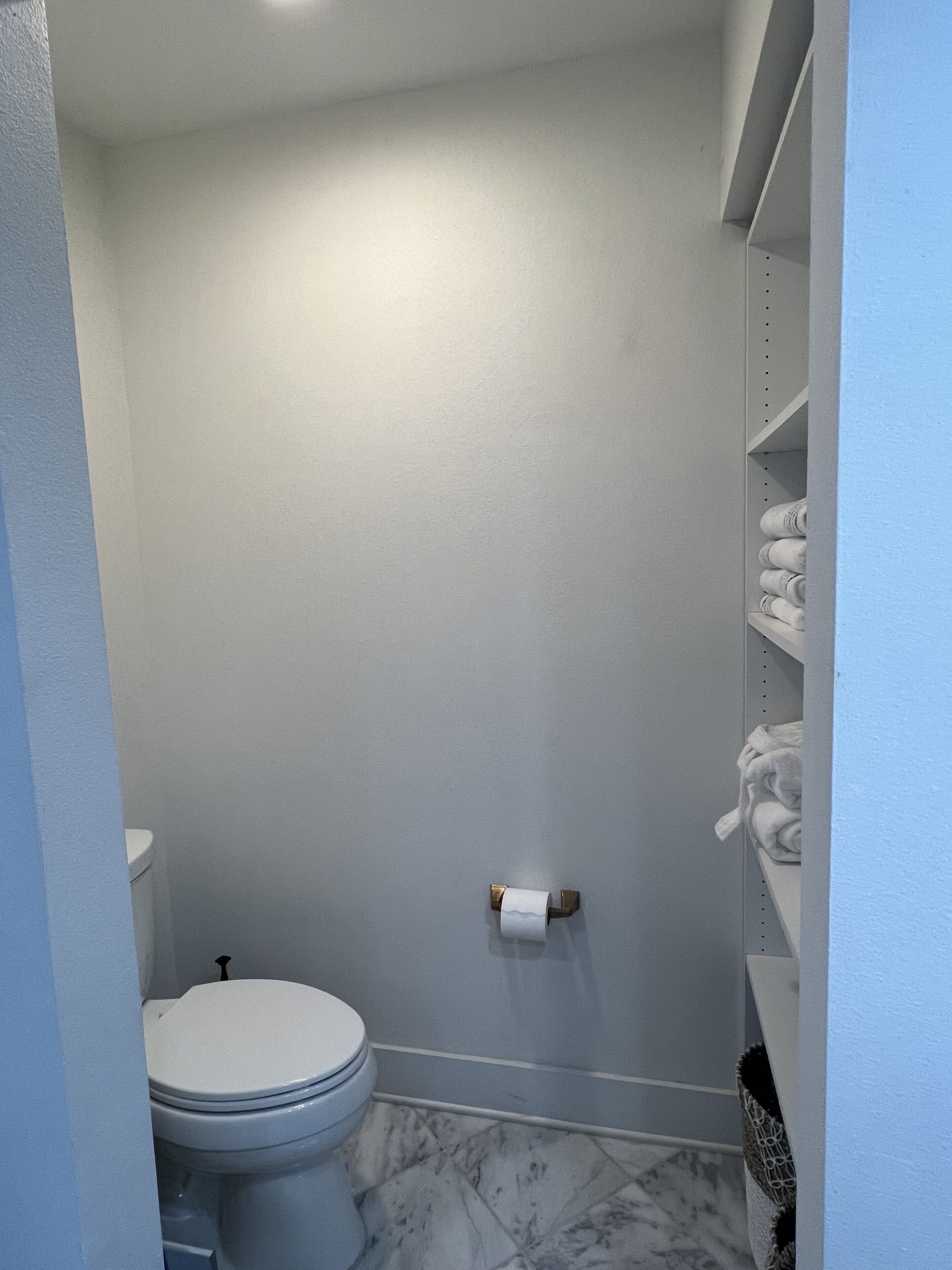 Ein Badezimmer mit Toilette, Toilettenpapier und einem Handtuchhalter mit Handtüchern.