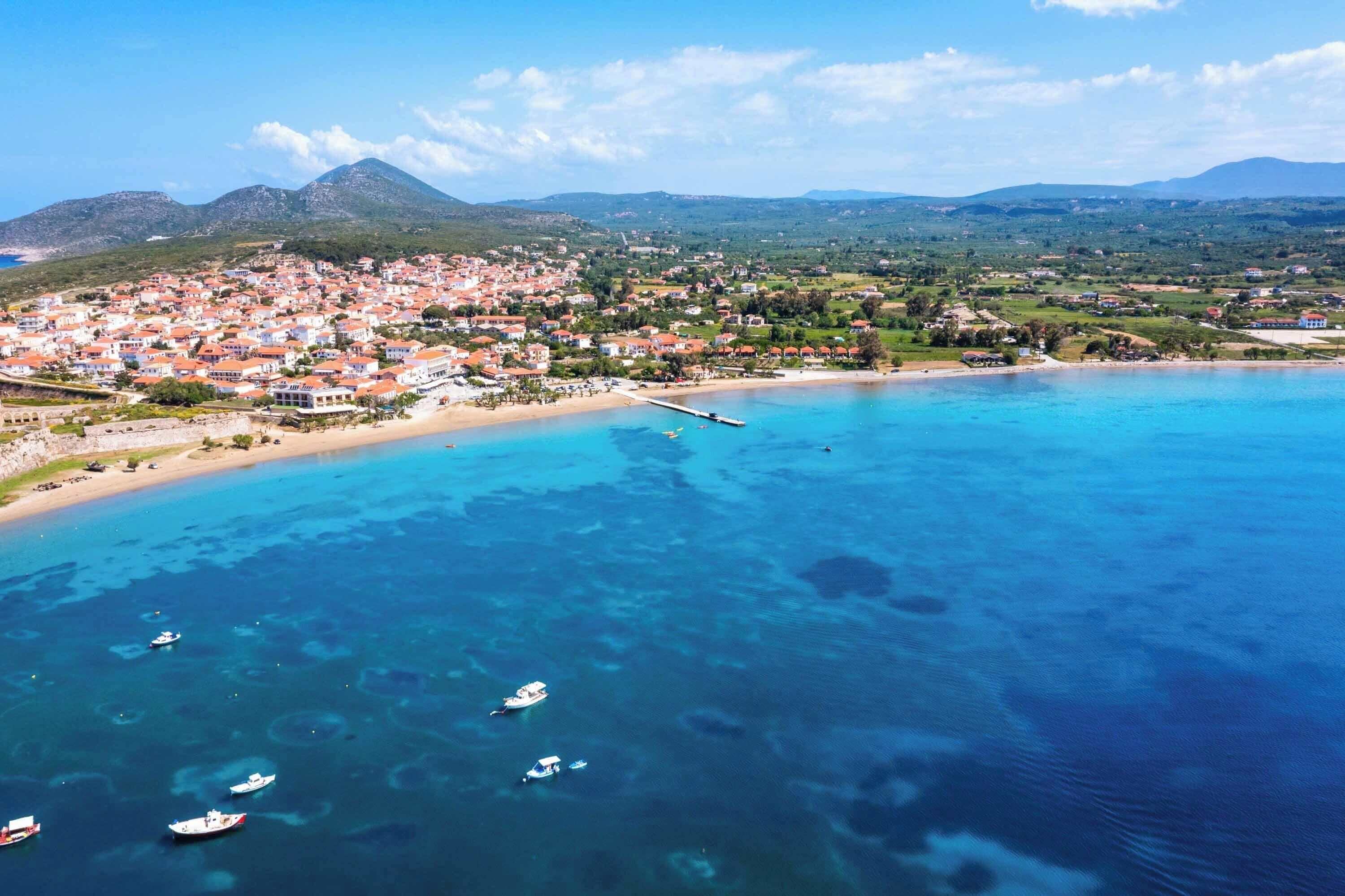 A coastal town with a beach, boats, and a pier.