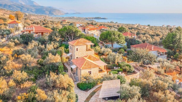 A coastal village with stone buildings, terraced gardens, and a view of the sea.