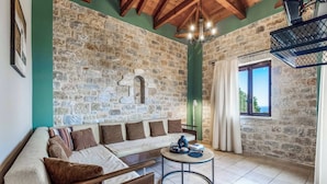 A cozy room with a stone wall, a wooden ceiling, a sofa, a coffee table, and a window with curtains.