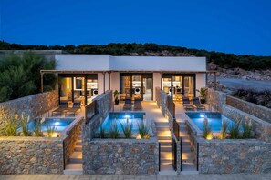 A modern villa with a pool, outdoor seating, and a stone wall surrounding the pool area. - Villa Kiotari Sky - One Bedroom Villa, Sleeps 2 (Kiotari)