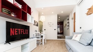 Ein modernes Wohnzimmer mit Flachbildfernseher, weißen Möbeln und einem grauen Sofa.