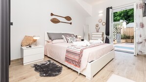 Ein modernes Schlafzimmer mit Bett, Nachttischen, einem Spiegel und Blick ins Freie.