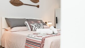 Ein ordentlich bezogenes Bett mit einer gemusterten Decke, Kissen und einer Nachttischlampe.