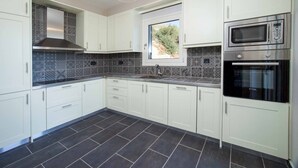 Een moderne keuken met witte kastjes, een roestvrijstalen afzuigkap, een magnetron en een oven.