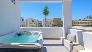 Un jacuzzi sur un balcon avec vue sur les bâtiments et un palmier.