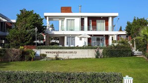 A modern two-story house with a balcony, a chimney, and a well-maintained lawn. - Villa Cyan Paphos - Three Bedroom Villa, Sleeps 6 (Pafos)