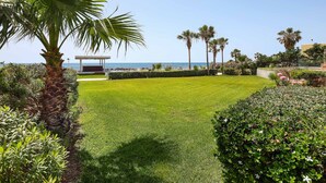A well-maintained lawn with a palm tree and a small structure, likely a gazebo, near a body of water. - Villa Cyan Paphos - Three Bedroom Villa, Sleeps 6 (Pafos)