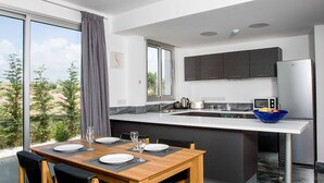 Una cocina moderna con una isla grande, armarios oscuros y vistas al exterior.