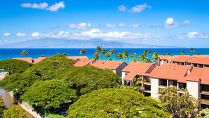 A resort with multiple buildings, a beach, and a view of a mountain range.