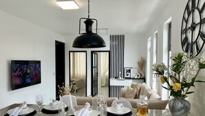 Un comedor moderno con una isla grande, un televisor en la pared y un reloj decorativo.