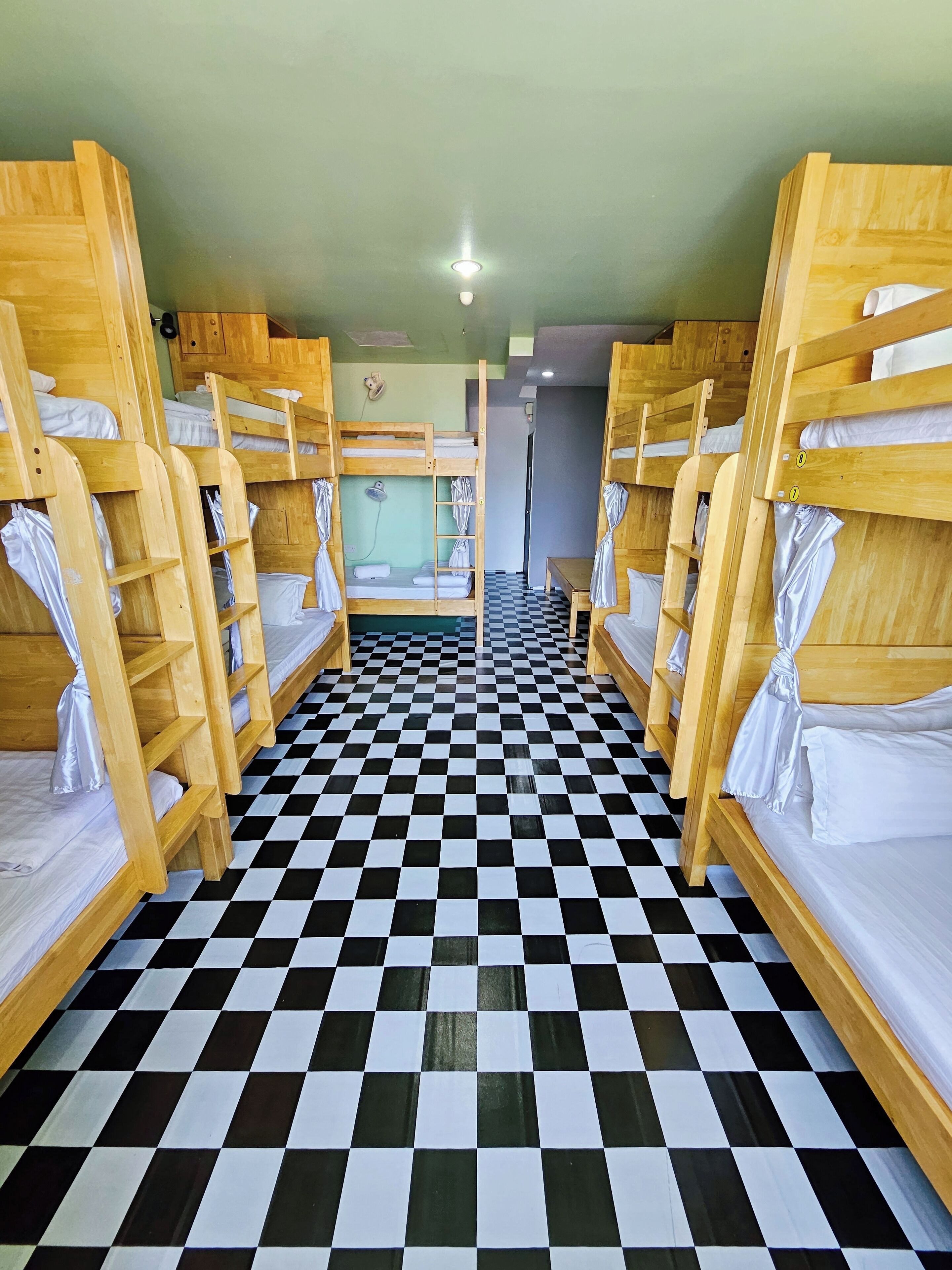 A room with bunk beds arranged in two rows, a checkered floor, and a small table in the center.