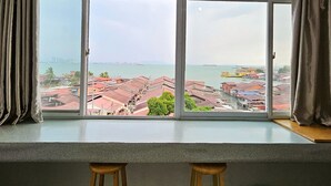 A room with a large window overlooking a cityscape, two wooden stools, and a checkered floor. - The 60 (George Town)