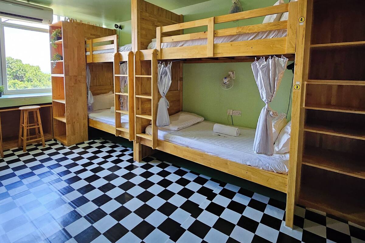 A room with bunk beds, a checkered floor, and a window.