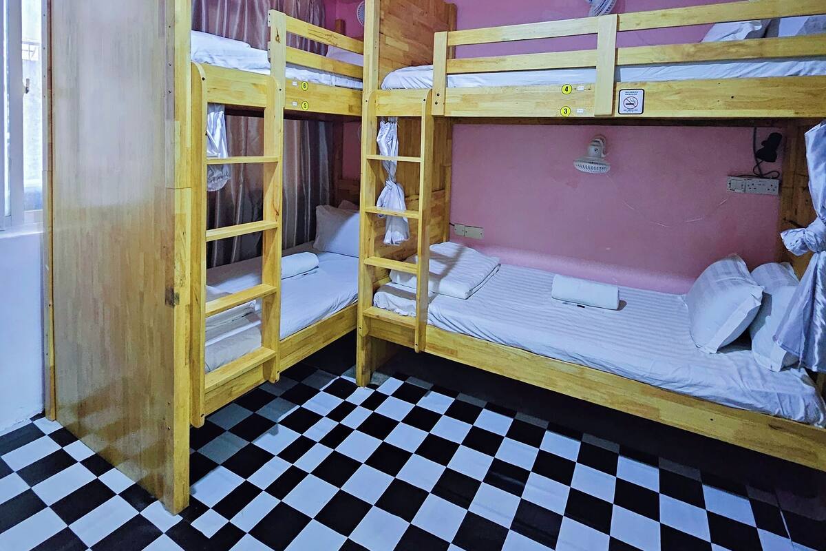 A room with three bunk beds, a checkered floor, and pink walls.