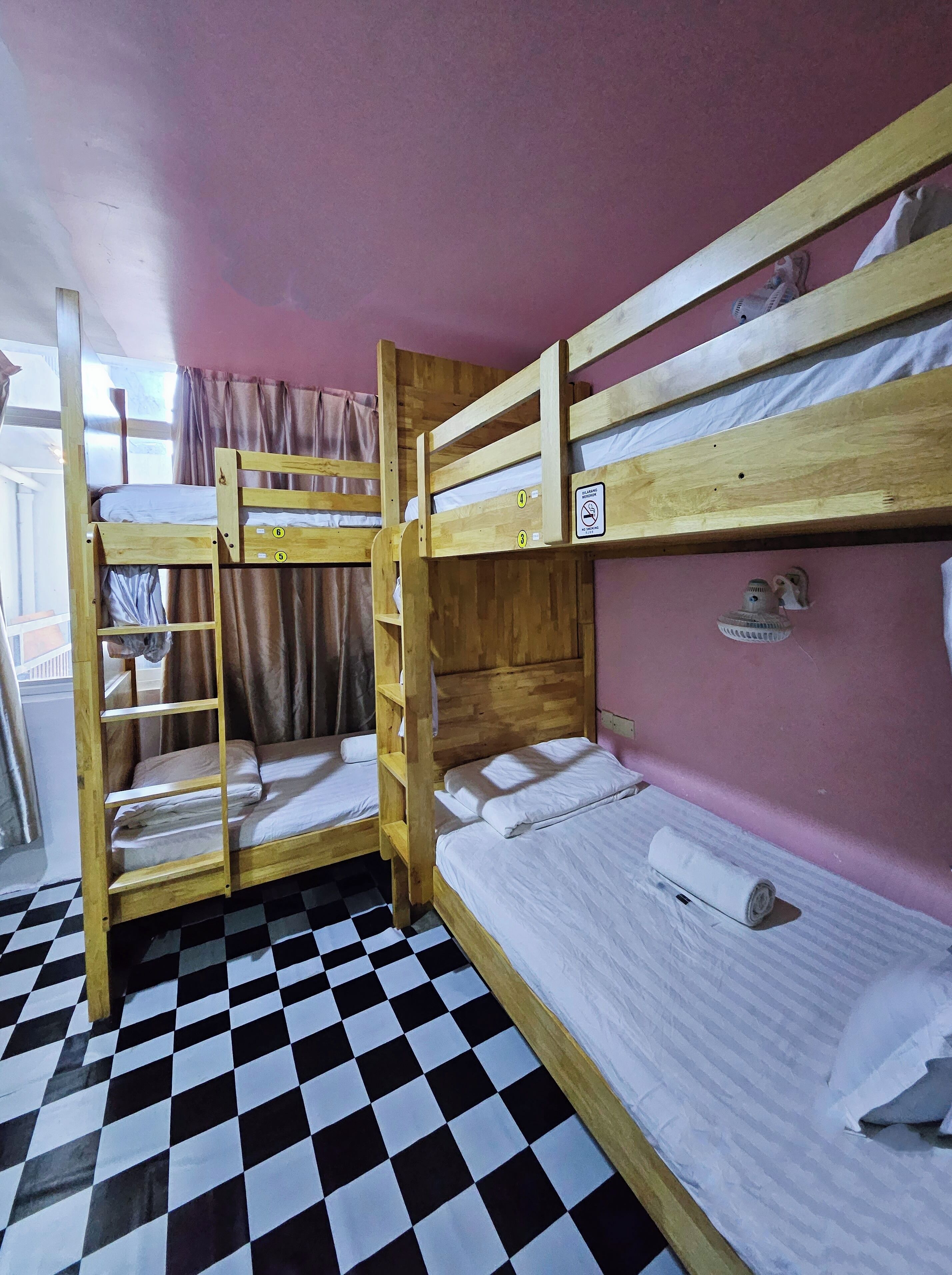 A room with bunk beds, a checkered floor, and a pink wall.