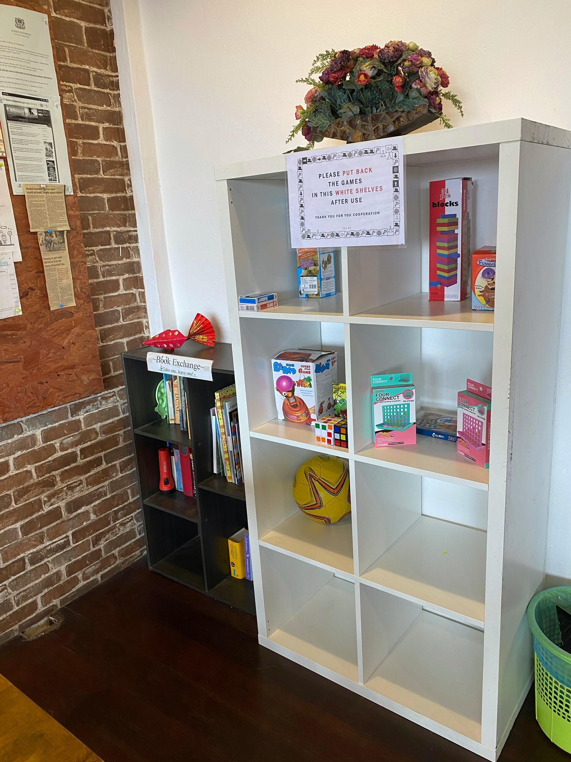 A bookshelf with various games and a sign instructing to put back games in the white shelves after use.
