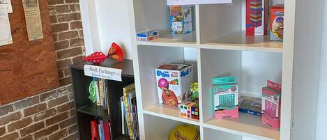 A bookshelf with various games and a sign instructing to put back games in the white shelves after use.