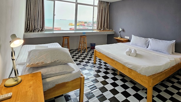 A hotel room with two beds, a checkered floor, a large window with a view, and a desk with a lamp. - The 60 (George Town)
