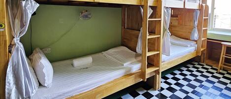 A bunk bed room with a checkered floor, green walls, and a window.