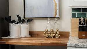 A kitchen counter with utensils, glass bottles, and a monkey figurine.