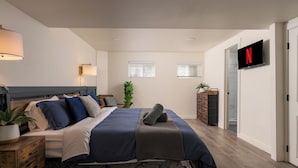 A bedroom with a bed, bedside tables, a TV, a wardrobe, and a plant.