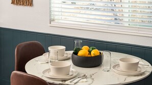 A dining table with white plates, bowls, and cutlery, a bowl of lemons and limes, and a glass. - Modern 2BR Denver Retreat w/ King Beds + Full Kitchen Near Arvada & Downtown! (Denver)