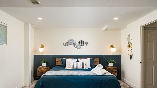 A bedroom with a bed, two bedside tables, wall sconces, and a decorative wall piece. - Stylish 1BR King Bed Garden Level Denver Retreat, w/ Full Kitchen Near Downtown (Denver)