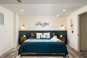 Une chambre à coucher comprenant un lit, deux tables de chevet, des appliques murales et un élément décoratif fixé au mur.
