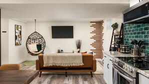 A modern kitchen with a built-in oven, a hanging chair, and a dining area with a wooden table and chairs. - Stylish 1BR King Bed Garden Level Denver Retreat, w/ Full Kitchen Near Downtown (Denver)