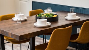A dining table set with white plates, bowls, and glasses, surrounded by yellow chairs. - Stylish 1BR King Bed Garden Level Denver Retreat, w/ Full Kitchen Near Downtown (Denver)