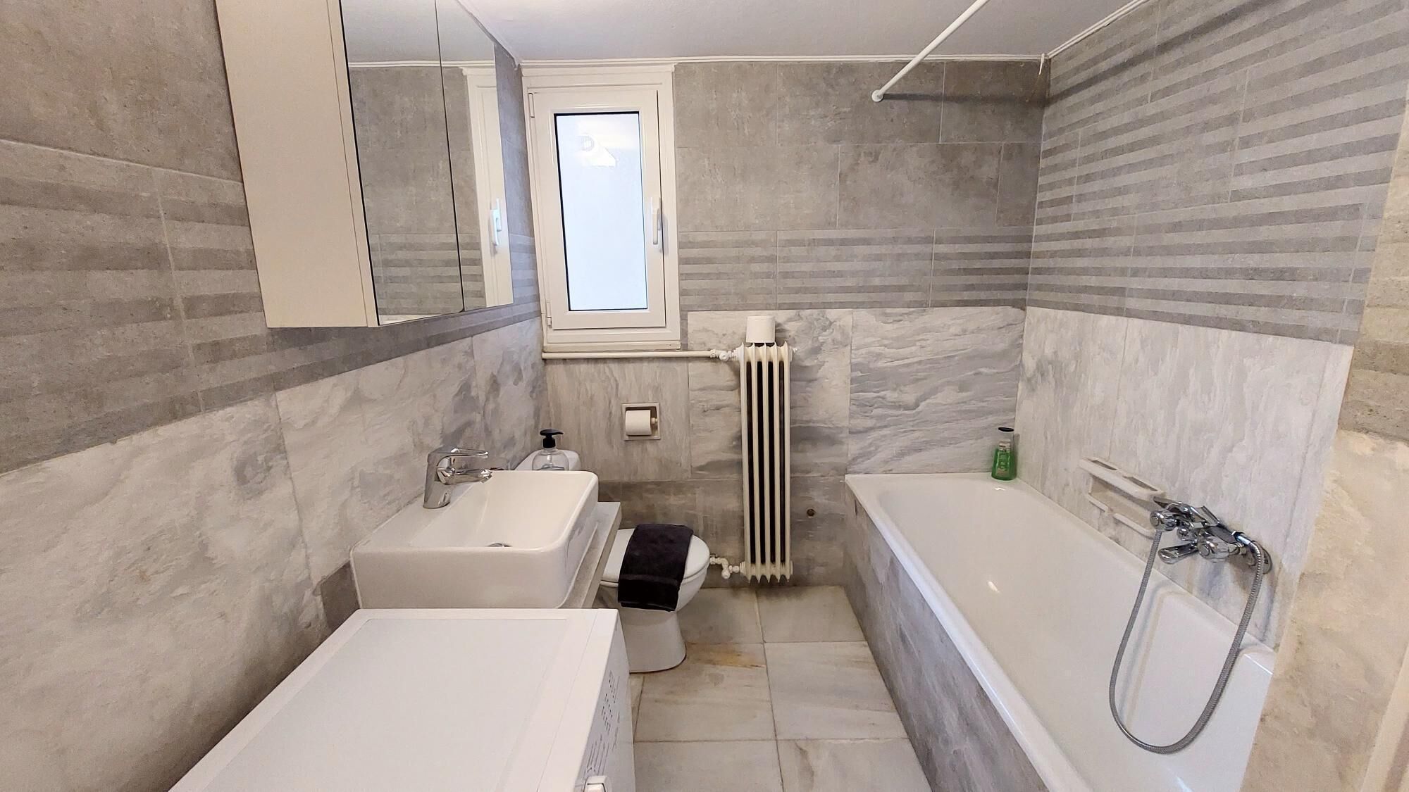 Un bagno moderno con vasca, lavandino e servizi igienici.
