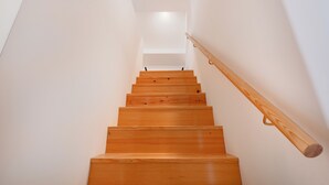 A wooden staircase with a handrail, leading to a landing with a light fixture. - Atelier by the Sea (Porto)