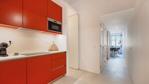 A modern kitchen with red cabinets, a microwave, and a coffee machine. - Atelier by the Sea (Porto)