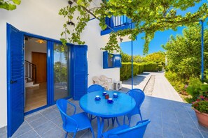 A blue outdoor dining area with a table and chairs, a blue door, and a view of a garden. - Villa Rotiana - Three Bedroom Villa, Sleeps 6 (Poli Crysochous)